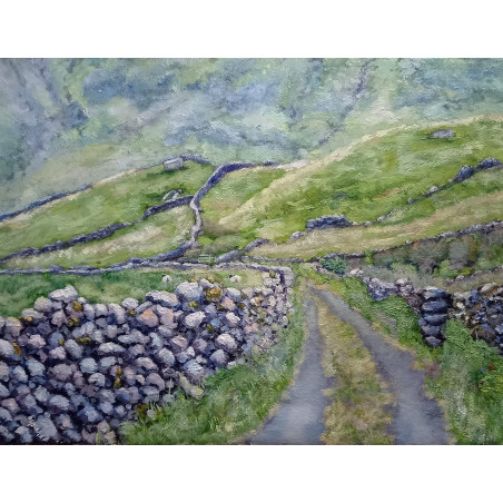 Quiet green road with old stone wall and hills in the Irish countryside